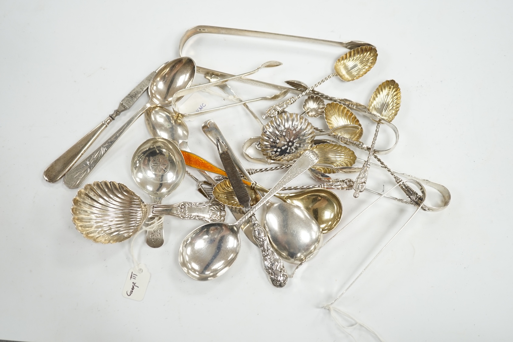 A collection of assorted small silver, sterling and white metal flatware, including two 19th century caddy spoons, enamelled spoon, sifter spoon, teaspoons, sugar tongs, etc. 9oz and two nail implements. Condition - poor